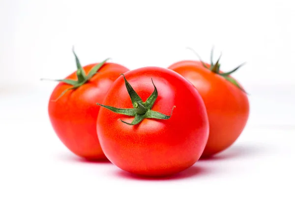 Três tomates vermelhos maduros sobre fundo isolado branco, close-up — Fotografia de Stock