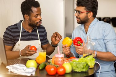 Mutfakta dizüstü bilgisayar kullanan iki adam
