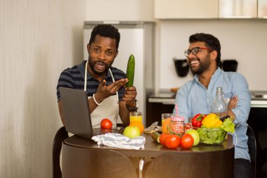 Mutfakta dizüstü bilgisayar kullanan iki adam