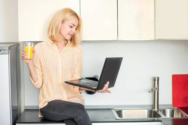 Жінка використовує ноутбук на кухні — стокове фото