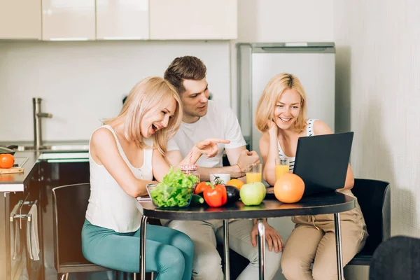 Друзья используют ноутбук на кухне — стоковое фото