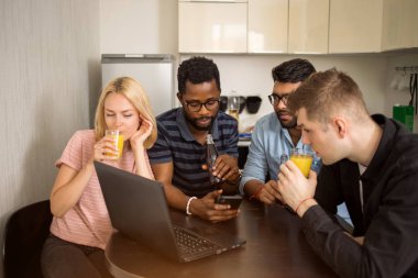 Dizüstü bilgisayar kullanarak masada oturan bir grup genç