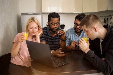 Dizüstü bilgisayar kullanarak masada oturan bir grup genç