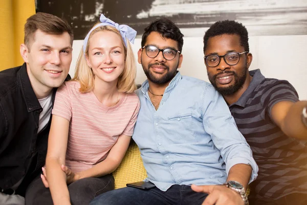 Vrolijke multi-etnische vrienden zittend op een bank — Stockfoto