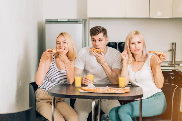 Jóvenes amigos comiendo pizza en la cocina y sonriendo — Foto de Stock