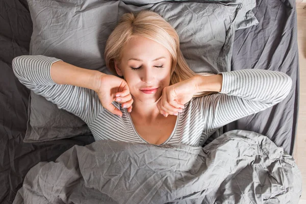 Kvinna stretching i sängen efter vakna — Stockfoto