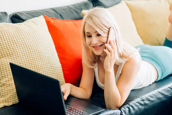 Jovem mulher usando laptop enquanto relaxa no sofá — Fotografia de Stock