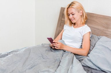 Yatakta telefon kullanan güzel genç kadın