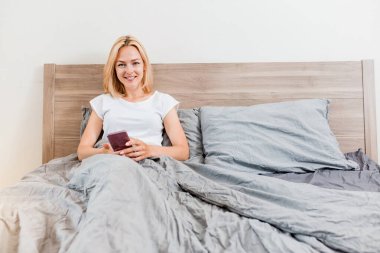 Yatakta telefon kullanan güzel genç kadın