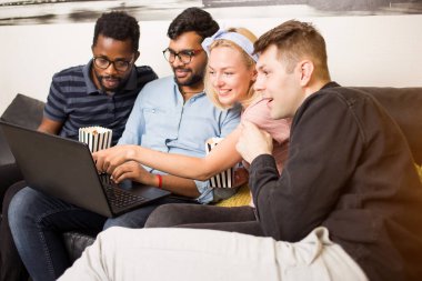 Dizüstü bilgisayar kullanarak ve gülerek bir grup arkadaş