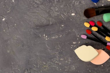 Çok renkli güzel göz farı ve makyaj fırçaları yakın plan, fotokopi alanı ve üst görünümü olan gri arka planda yüz süngerleri.