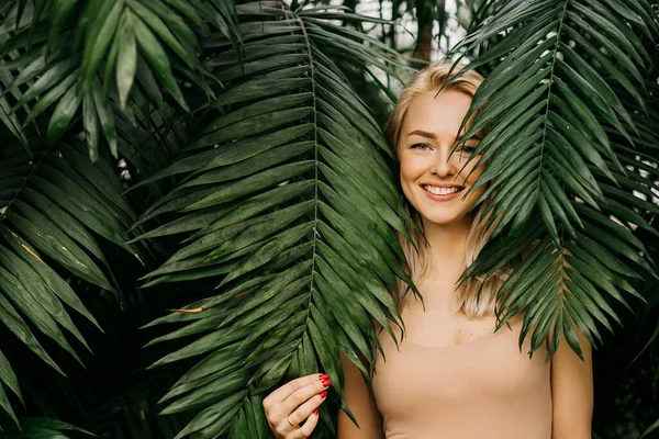 具有自然的裸体妆容 完美的皮肤 金发的快乐女士的画像 躲在棕榈叶后面的漂亮女人化妆品 — 图库照片