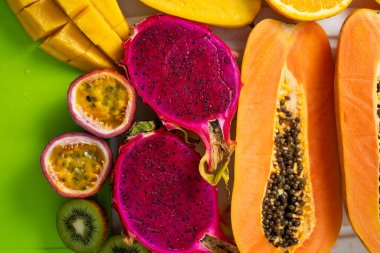 Beyaz tepside dilimlenmiş tropik egzotik meyveler. Üst Manzara. Kapatın. Çiğ papaya, portakal, mango, ejderha meyvesi, kivi ve marakujdan oluşan sağlıklı bir vejetaryen kahvaltısı. Yaz, yemek konsepti.