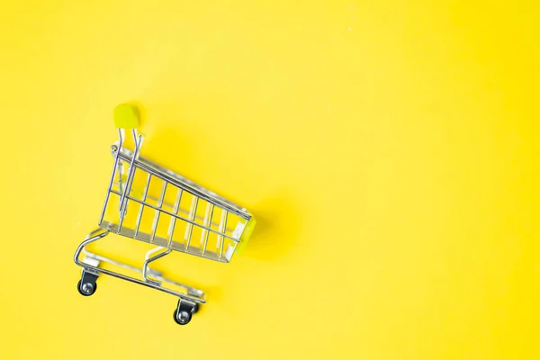 Empty shopping cart isolated on yellow background with copy space for text or design. Top view, flat lay of shopping trolley. Supermarket, shopping, sale concept.