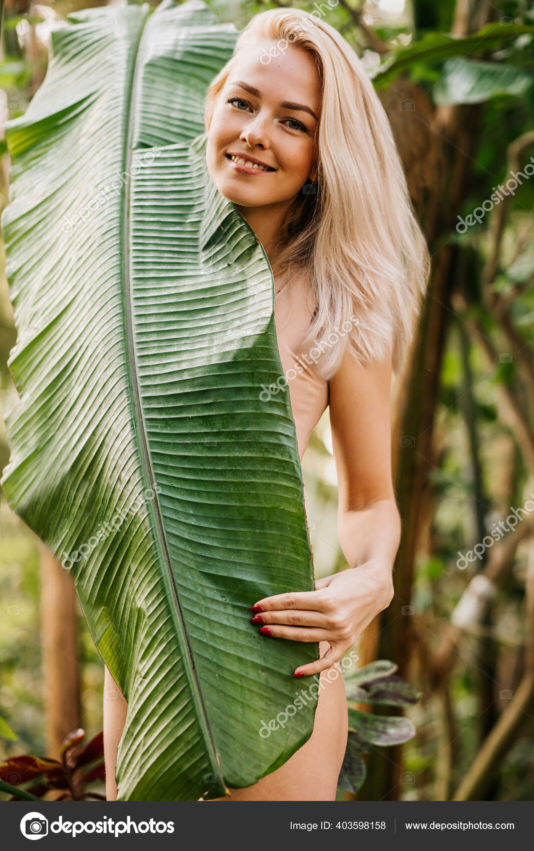Descarregar - Mulher loira bonita boa aparência em maiô cor de carne elegante apreciando a natureza, posando na floresta, cobrindo corpo esbelto atrás de grande folha de planta exótica. Modelo de moda, conceito de beleza. — Imagem de Stock Mulher Loira Bonita Boa Aparência Maiô Cor Carne Elegante Apreciando — Fotografia de Stock