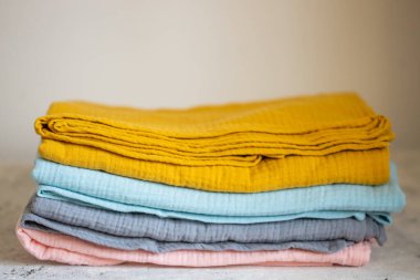 Pembe, mavi, hardal, gri muslin kumaşlar, beyaz arka planda bebek bezi.