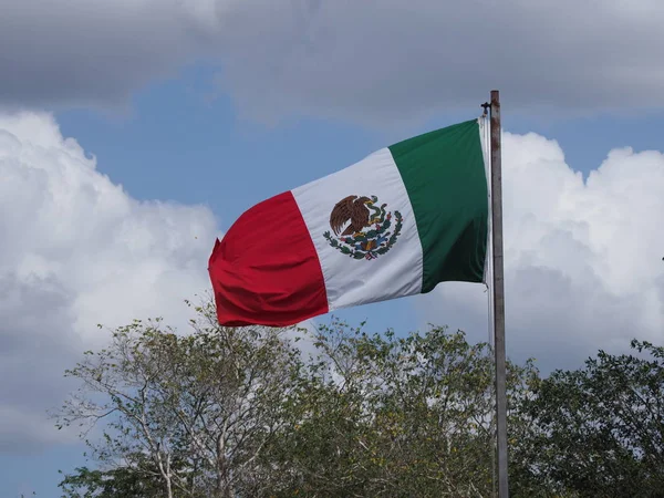 Bandera máxima nacional en la ciudad de Chichén Itzá cerca del sitio arqueológico en México con árboles y cielo nublado —  Fotos de Stock