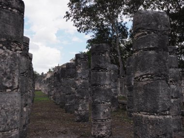 Meksika 'nın Chichen Itza Maya kasabasındaki Bin Savaşçı Tapınağı' ndaki antik sütunlar, 2018 'de bulutlu mavi gökyüzü olan arkeolojik bölgede harabeler, sıcak kış günü, Kuzey Amerika.