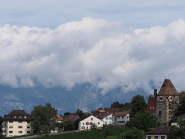 Avrupa 'nın başkenti Vaduz, Lihtenştayn' ın üzerindeki şehir manzarasının tepesindeki taş kule ve güzellik konutları 2018 'de sıcak bir yaz günü bulutlu bir gökyüzü altında..