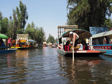 XOCHIMILCO, MEXICO Mart 2018: birkaç tekne turist ve gondolcuyla Meksika 'nın şirin yüzen bahçelerinde güneşli bir kış gününde açık mavi gökyüzü.