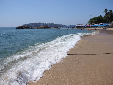 Koltuklar ve Acapulco bay City Meksika Pasifik Okyanusu'nun beyaz dalgalar ile kumlu plajda palmiye ağaçları