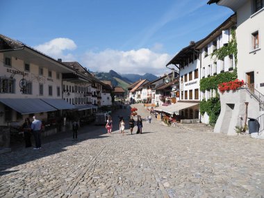 GRUYERES, SWitness ZERLAND, Ağustos 2018: Sıcak, güneşli yaz gününde açık mavi gökyüzü ile Fribourg kantonundaki İsviçre Avrupa kantonundaki ana pazar meydanındaki eski evlere bakın.