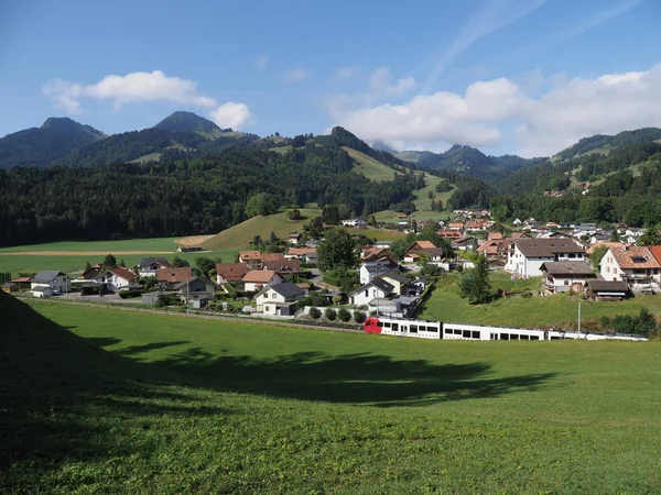 Alpenpanorama mit Häusern und Zug in der europäischen Gruyeres-Stadt in der Schweiz im August — Stockfoto