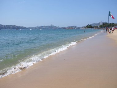 Meksika ulusal bayrağı ve Meksika 'nın Pasifik Okyanusu' ndaki Acapulco şehrinin körfezindeki güneşli yataklarıyla muhteşem bir manzara.