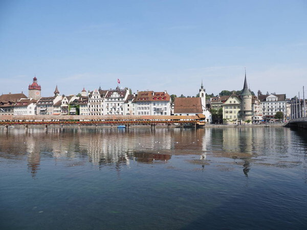 LUCERNE, SWITZERLAND on AUGUST 2018: Panoramic view to historical buildings and chapel bridge at Reuss river in european city landscapes with clear blue sky in warm sunny summer day.