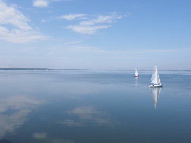GOCZALKOWICE, POLAND MAYIS 2019: Ilık bir bahar gününde mavi gökyüzünde bulutları olan yapay Avrupa rezervlerinin güzellik manzaraları üzerinde iki beyaz yat.