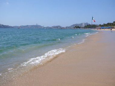 Meksika ve Pasifik Okyanusu peyzaj Acapulco Şehir Körfezinde büyük Meksika Ulusal bayrağı ile pitoresk turkuaz dalgalar