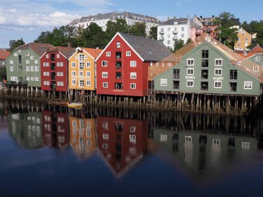 TRONDHEIM, NORway, Temmuz 2019: Avrupa 'nın Nidaros şehrindeki Nidelva nehrindeki liman ve renkli binalar ılık güneşli yaz gününde açık mavi gökyüzü.