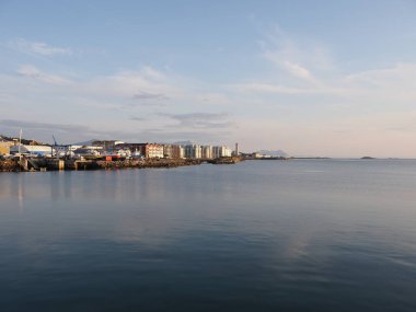 Norveç 'in Salten bölgesindeki Avrupa kenti Bodo' da gezinti yapılan körfezin manzarası, 2019 yılında güneşli bir yaz gününde Temmuz 'da gün batımında açık mavi gökyüzü.