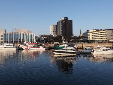 BODO, NORWAY on JULY 2019: Cityscape and promenade with yachts and hotels reflected in water in european city at Salten region with clear blue sky in warm sunny summer day at sun set.