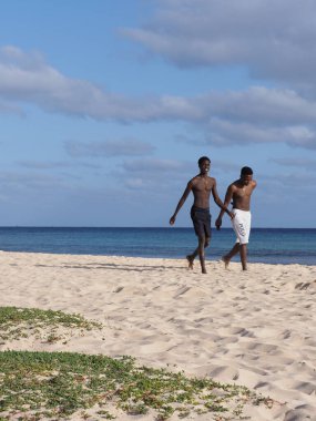 SANTA MARIA, CAPE VERDE Mart 2019: Atlantik Okyanusu kıyısında iki siyah adam Sal Adası 'ndaki Afrika kasabasında, ılık güneşli bahar gününde açık mavi gökyüzü -.