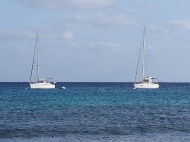 Atlantik Okyanusu 'nun berrak turkuaz sularındaki iki beyaz yat Cape Verde' deki Afrika Sal Adası 'nda, ufuk çizgisi ve 2019' da ılık güneşli yaz gününde açık mavi gökyüzü..