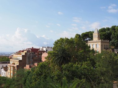 İspanya 'nın Katalonya bölgesindeki Barselona şehrinin renkli şehir manzarası ve Park Guell' in giriş binasının bacası, 2019 yılının ılık güneşli yaz günü bulutlu mavi gökyüzü.