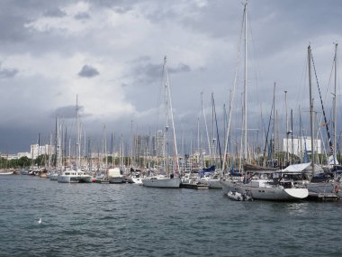 BARCELONA, SPAIN SEPTEMBER 2019: Avrupa 'nın Katalonya bölgesindeki liman kentinde beyaz yatlar ve botlar, soğuk yaz günlerinde bulutlu gökyüzü.