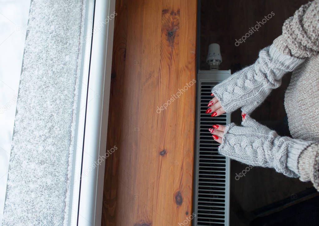 Woman warming hands on hot battery