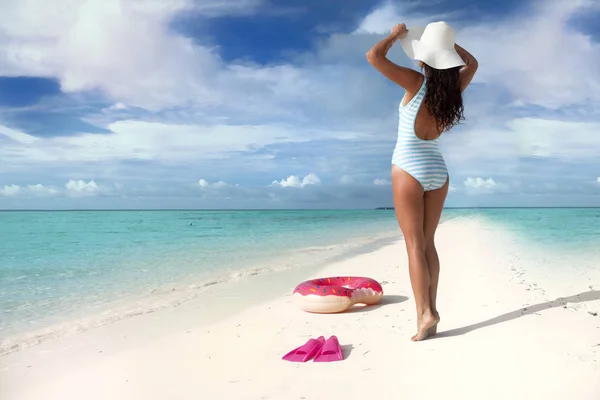 ピンクのドーナツのようなインナー チューブとビーチで休んで若いブルネットの女性 — ストック写真