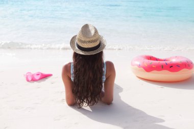 Genç esmer kadın iç tüp pembe çörek gibi birlikte kumsala dinlenme 