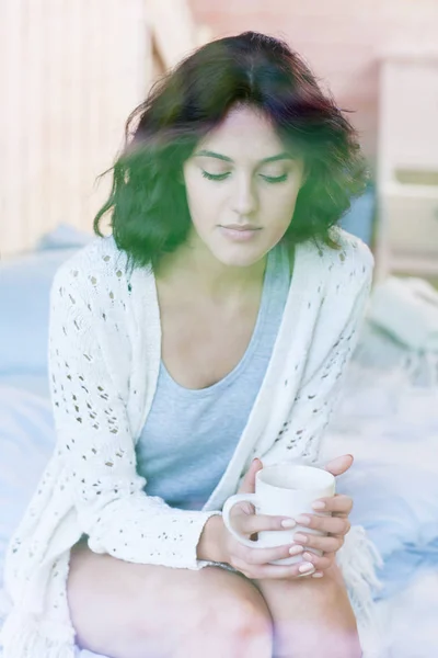 Femme Réfléchie Assise Sur Lit Avec Une Tasse Thé Blanc — Photo