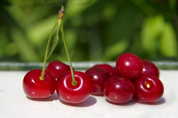 白いテーブルの上とグレの上にチェリーの赤いジューシーな熟した果実 — ストック写真