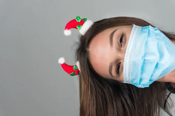 一个戴着医疗面罩的年轻女子从镜框后面往外看 验尸官大流行期间的圣诞时间 是的高质量的照片 — 图库照片