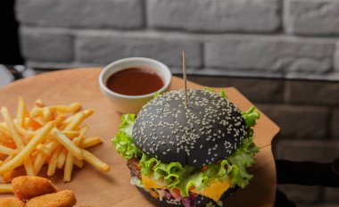 Patates ve sosu bir ahşap zemin üzerine siyah burger