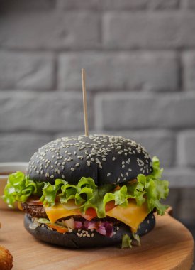 Patates ve sosu bir ahşap zemin üzerine siyah burger