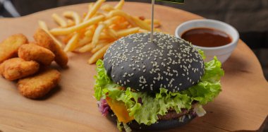 Patates ve sosu bir ahşap zemin üzerine siyah burger