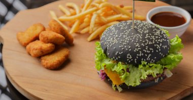Patates ve sosu bir ahşap zemin üzerine siyah burger