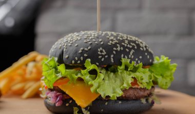 Patates ve sosu bir ahşap zemin üzerine siyah burger