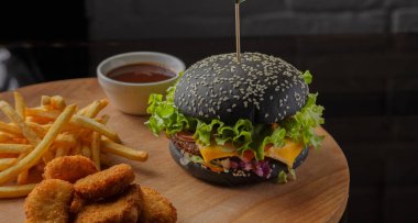 Patates ve sosu bir ahşap zemin üzerine siyah burger